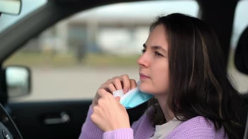 Woman Puts On Blue Face Mask in Car