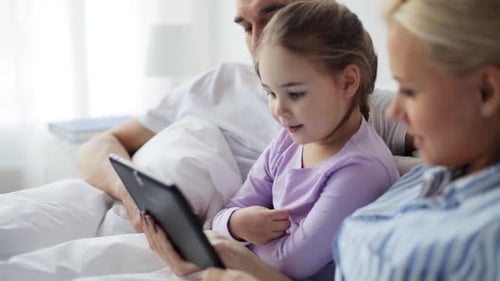 Family Uses Tablet in Bed Together at Home