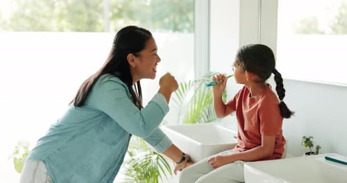 Woman and Girl Brushing Teeth in Bright Bathroom