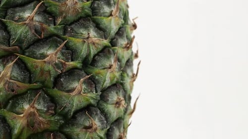 Ripe pineapple rotates on a white background.
