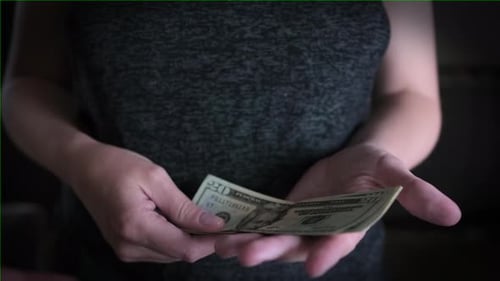 Woman Counting and Handing Over U.S. Dollar Bills