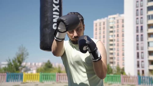 Man Boxing Outdoors with Punching Bag