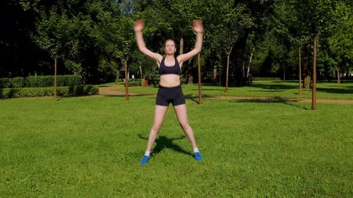 Woman Exercising Doing Jumping Jacks in the Park