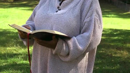 Woman Reads Bible in a Grassy Field