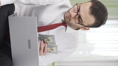 Young Adult Counting Money With Laptop