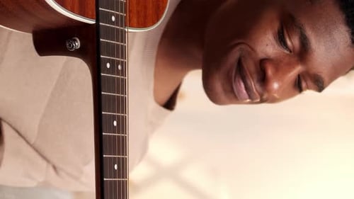 Young Man Plays Acoustic Guitar Indoors Close Up