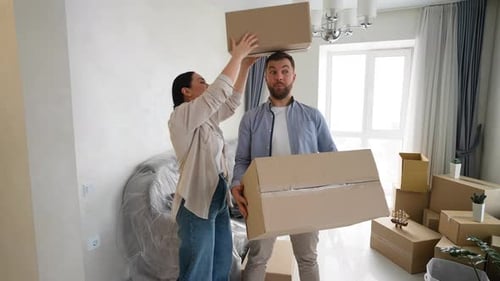 Happy Couple Playing with Cardboard Boxes While Moving Into New Home