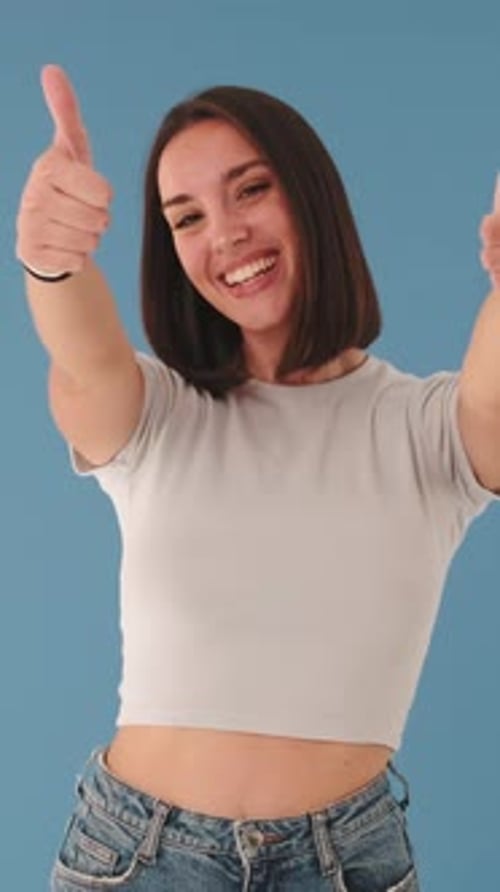 Smiling Woman Gives Thumbs Up on Blue Background