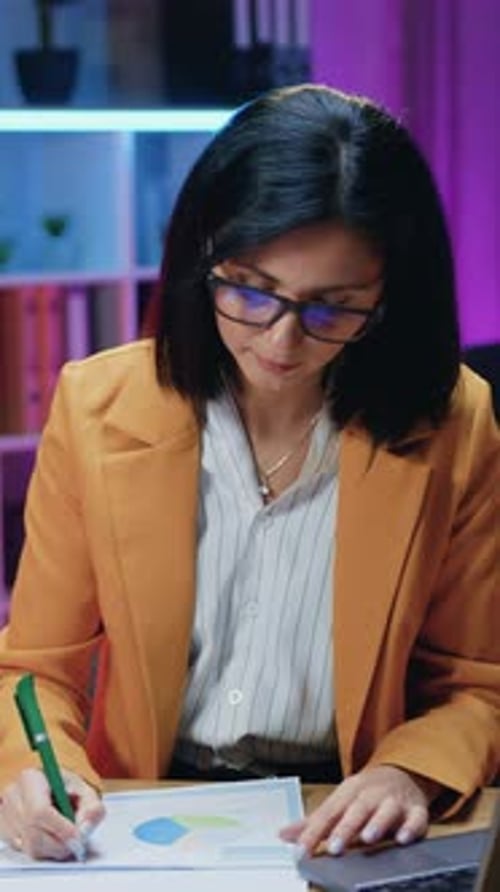 Businesswoman Working on Laptop and Reviewing Documents
