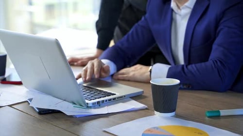 Man working on a laptop at desk. Laptop on office desk and business partners work in it.
