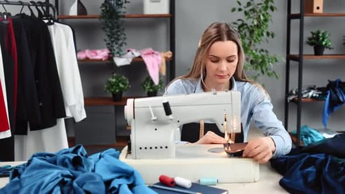Woman Sews Fabric with a Sewing Machine Indoors