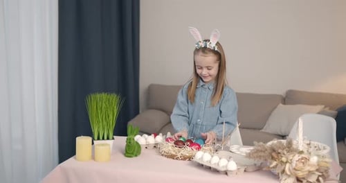 Kleines Mädchen malt Osterei auf einem Tisch zu Hause