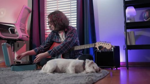 Young Adult Playing Guitar with Dog Nearby