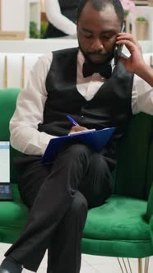 Young Adult on Phone Writing on Clipboard