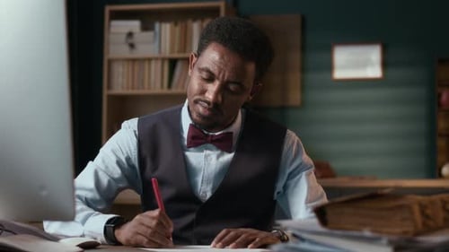 Tutor Grading Essays of Students at Table in Office