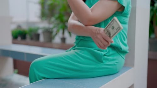 Close-up of woman counting money and counting dollar bills to pay daily expenses.