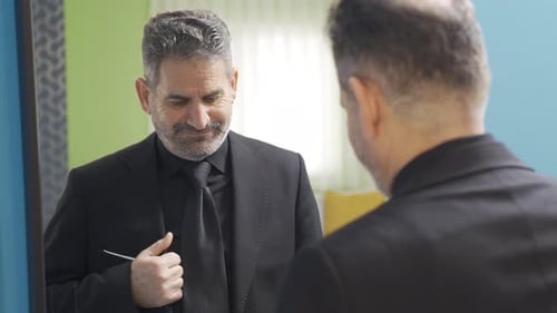 Man Adjusts Tie in Mirror, Black Suit