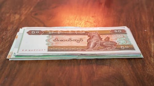 Colorful stack of money from around the world on a wooden table, close up.