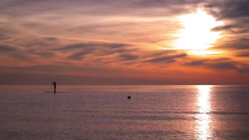 Silhouette Paddleboarding on the Ocean at Colorful Sunset
