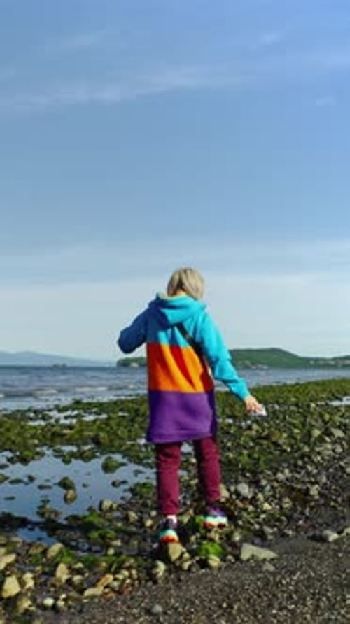 Woman Walking on Rocky Beach Towards Ocean View