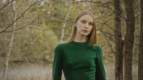 Model posing wearing green dress in autumn forest