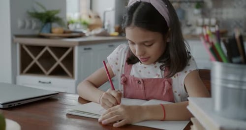 Young Girl Draws in Notebook at Home