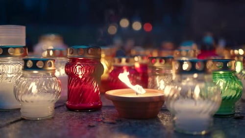 Grave Candles Lights Glowing on Cemetery at Night on All Saints Day