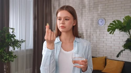 Young Woman Taking Pill with Glass of Water