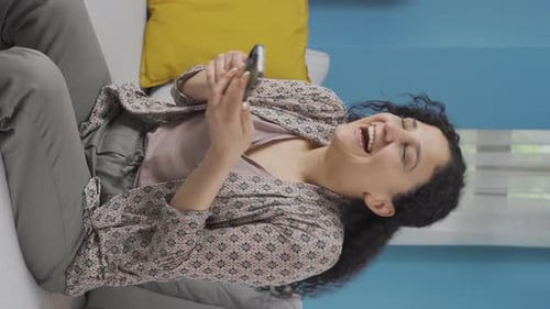 Vertical video of Young woman laughing at phone message.