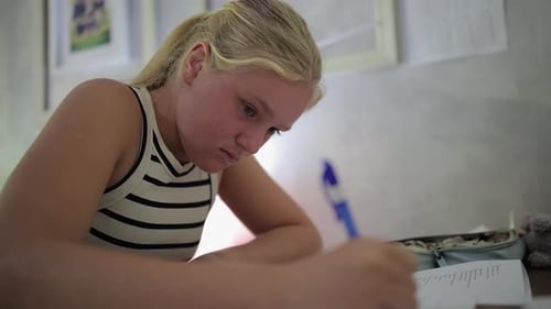 Close up: Teen girl does homework from school at her bedroom desk
