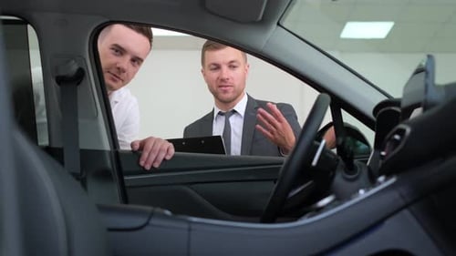 Salesman Shows Car to Potential Buyer in Showroom