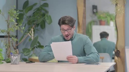 Man Reading Papers Reacts with Excitement