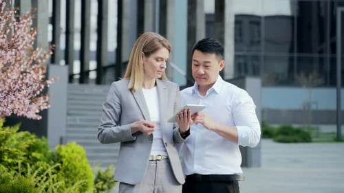 Two employees talking standing on a city street near office building. Using viewing Browsing
