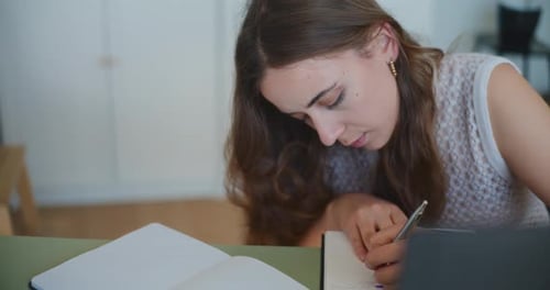 Woman Writing in Notebook at Table Indoors