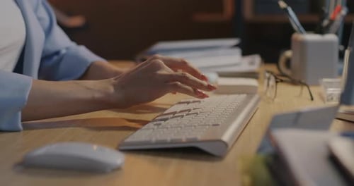 Nahaufnahme in Zeitlupe weiblicher Hände, die nachts mit der Computertastatur am Schreibtisch im Büro tippen