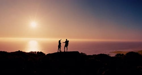Couple, silhouette and hiking with high five at sunset with ocean, sky and mock up space on vacation