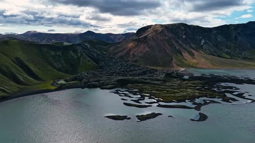 Aerial drone shot of turquoise crater lake in Landmannalaugar, Iceland, with lava stream and
