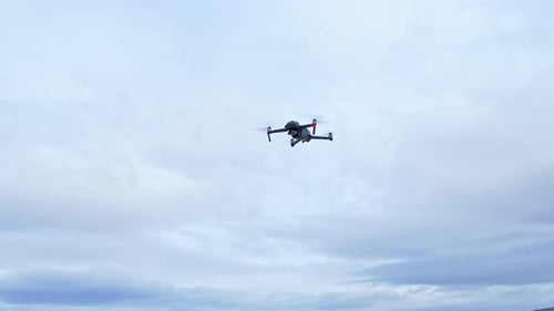 Drone in flight with position lights and signal flashes. Close aerial view.