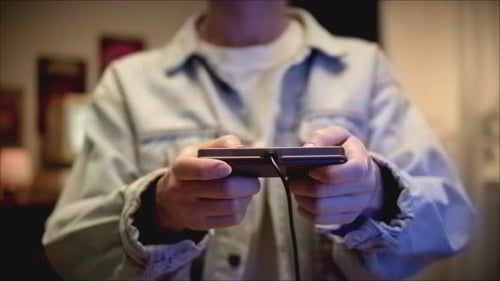 Hands Holding Wired Black Electronic Device Indoors