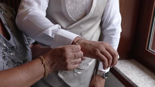 Mother Helping Groom with Cufflink Before Wedding