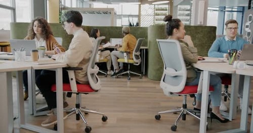Zoom sur des employés discutant de leur travail à l'aide d'un ordinateur portable à l'intérieur d'un espace de coworking moderne
