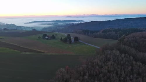 Highways Pass Through Valley with Forests Meadows and Village Shrouded in Mist in Evening Light