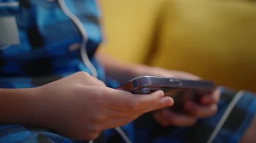 Child Uses Mobile Phone on Couch at Home