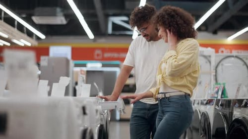 Couple choosing washing machine in electronics store in slow motion