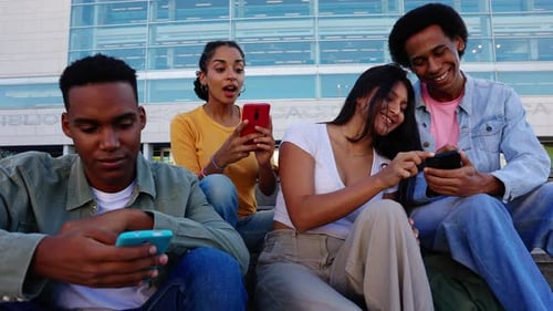 Happy Diverse Group of Young College Friends Having Fun Using Mobile Phones