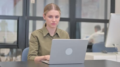Young Woman Working on Laptop Rubs Temples