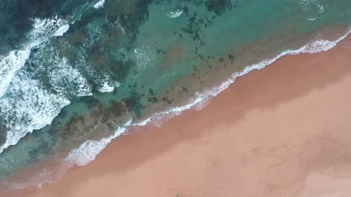 Pristine blue ocean waves crashing onto a beautiful beach. Rising bird's eye view