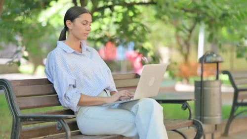 Woman Works on Laptop Outdoors, Experiences Headache