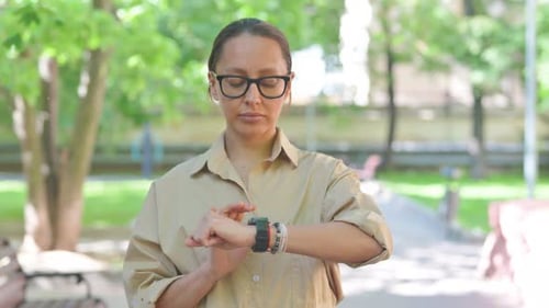 Multi Ethnic Woman Checking Her Smartwatch in a Park