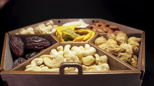 We eat dried fruits and nuts. Wooden box. Close-up, in motion